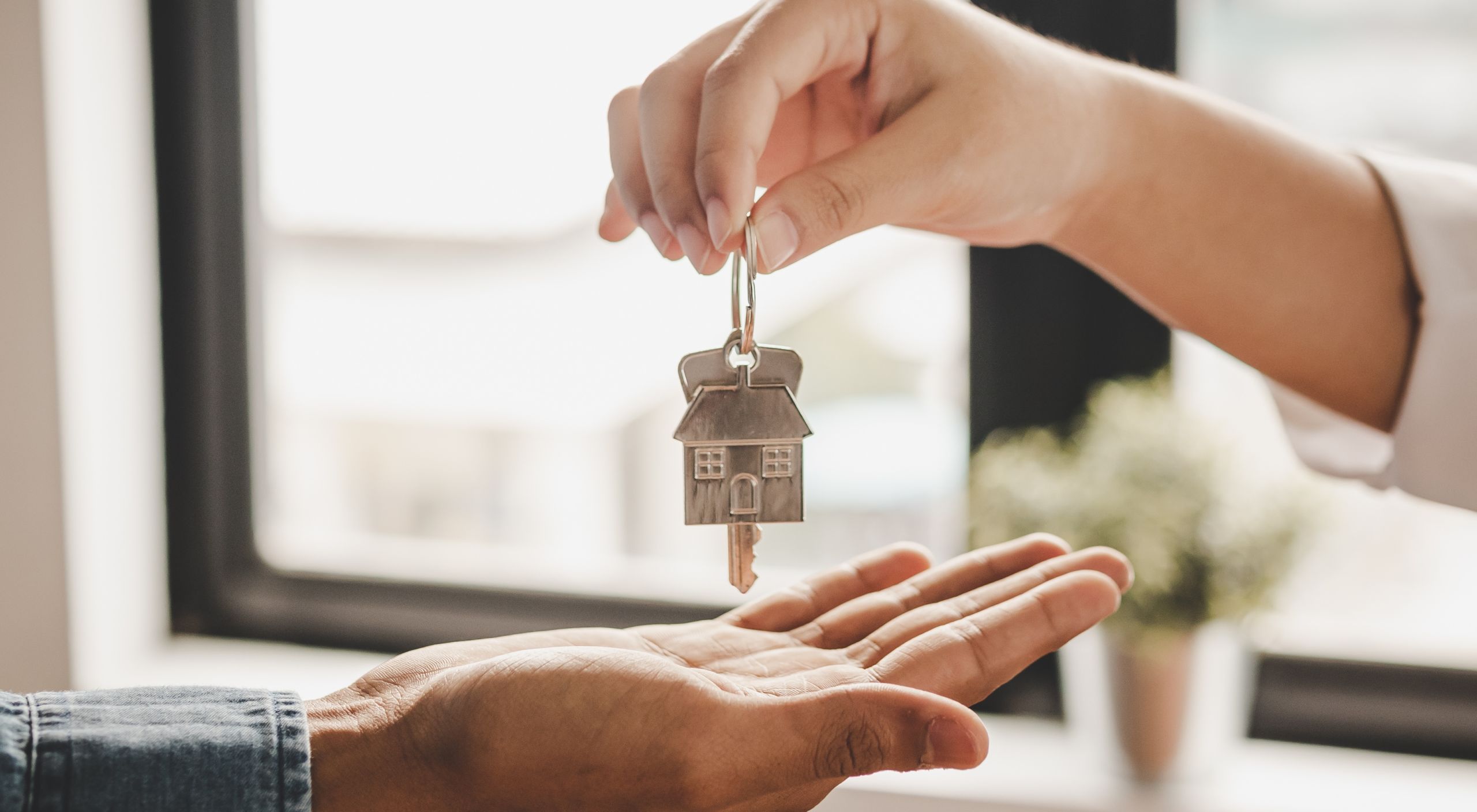 Close up hand of home,apartment agent or realtor was holding the key to the new landlord,tenant or rental.After the banker has approved and signed the purchase agreement successfully.Property concept.